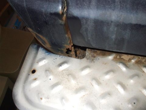 1979 Ford Bronco - Detail of a vehicle's lower body panel and step, revealing significant rust damage.