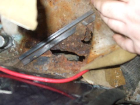 1979 Ford Bronco - This image shows significant rust and damage to a vehicle's metal components, with a red wire visible.