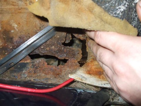 1979 Ford Bronco - Severe rust damage is visible on the vehicle's floor pan, with a large hole exposing the undercarriage.