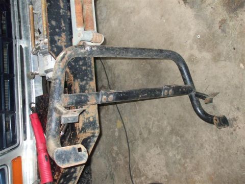 1979 Ford Bronco - A close-up view of a detached front bumper guard, showing its metal construction and mounting points.