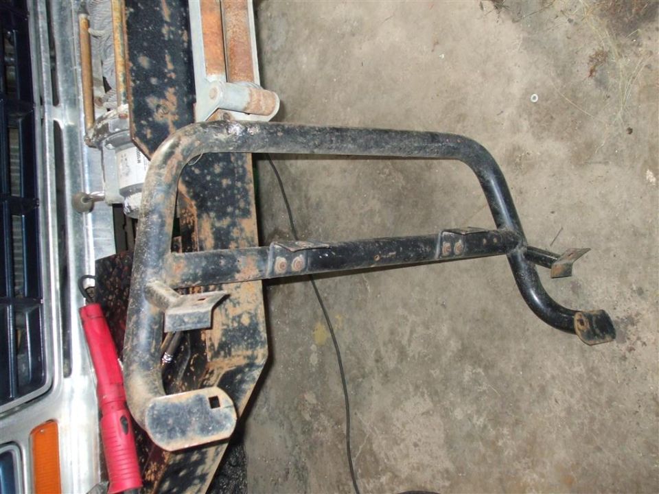 Black metal front bumper guard with two horizontal bars, mounted on a rusty frame