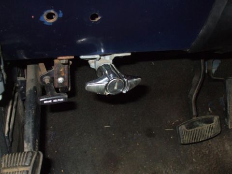 1979 Ford Bronco - Close-up of the brake release lever and ignition switch assembly under the dashboard.