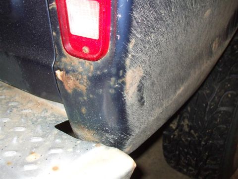 1979 Ford Bronco - Close-up of a vehicle's rear corner, revealing rust and dirt accumulation.