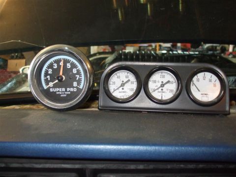 1979 Ford Bronco - A close-up view of a vehicle's dashboard, a Super Pro tachometer and a set of three Hastings gauges.