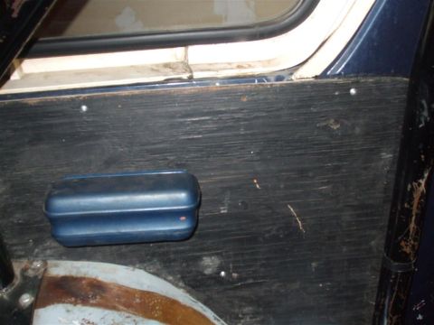 1979 Ford Bronco - Close-up of an interior door panel showing a blue armrest and wood grain texture.