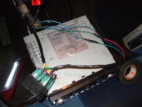1979 Ford Bronco - Close-up of a car stereo's wiring harness and connections, with electrical tape and a fuse holder in view.
