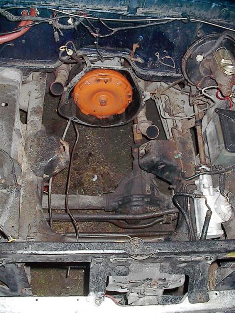 1979 Ford Bronco - Close-up view of the transmission and drivetrain components within the engine bay of a vehicle.
