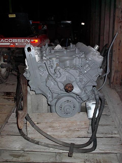 1979 Ford Bronco - Engine assembly, likely for a Ford Bronco, sits on wooden planks. A Jacobsen tractor is visible in the background.