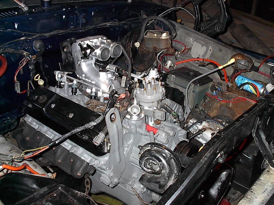 Engine bay showing a V8 engine with aftermarket intake manifold and distributor