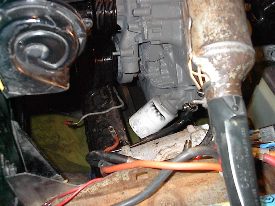 Engine compartment with gray painted engine block, oil filter, and various hoses and wires