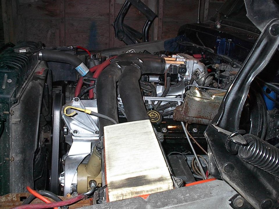 Engine bay with large black hoses, a radiator, and a brake fluid reservoir