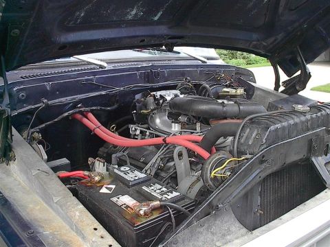 1979 Ford Bronco - The engine bay of a dark blue vehicle is shown with various components and wiring visible.