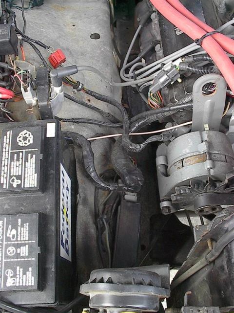 1979 Ford Bronco - The engine bay of a vehicle, the battery, alternator, and various electrical components.