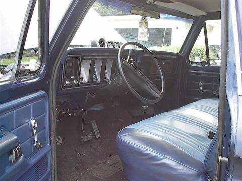 1979 Ford Bronco - The interior of a blue 1979 Ford Bronco features a blue bench seat and aftermarket gauges mounted on the dashboard.