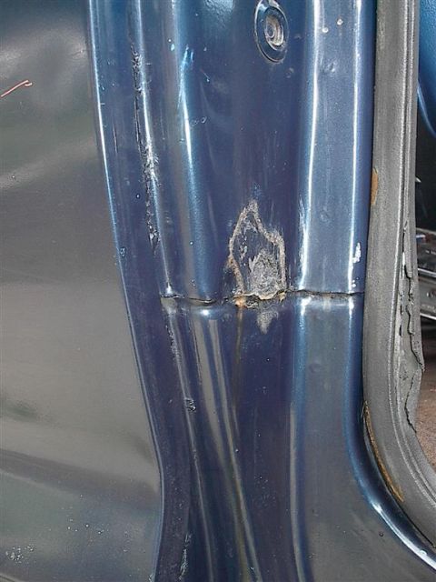 1979 Ford Bronco - Close-up of rust forming on the door jamb of a blue vehicle.