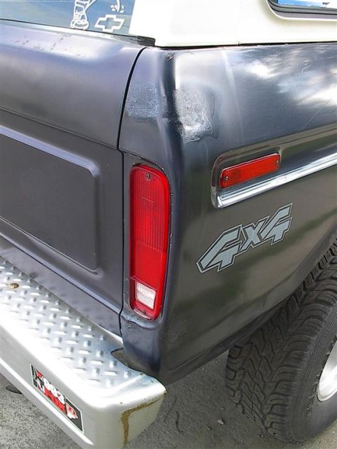 1979 Ford Bronco - Close-up of the rear passenger side of an SUV, showing the taillight, '4x4' decal, and chrome bumper.