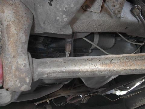 1979 Ford Bronco - The underside of a vehicle reveals suspension components and exhaust system parts, with visible signs of wear and tear.