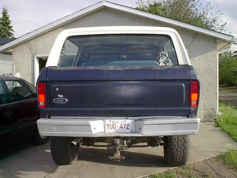 1979 Ford Bronco - Rear view of a dark blue 1978 Ford Bronco with a white hardtop, parked in front of a garage.