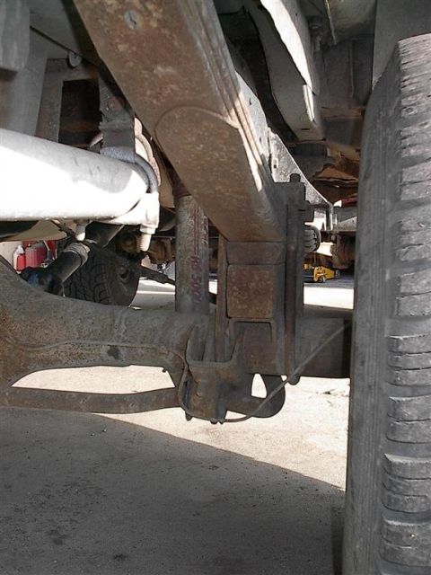 1979 Ford Bronco - Vehicle's rear leaf spring suspension system shows signs of rust and wear.