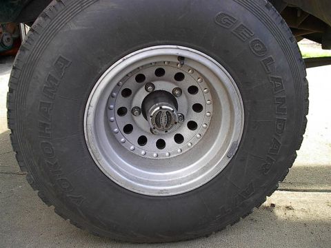 1979 Ford Bronco - Close-up of a Yokohama Geolandar tire and silver rim with a chrome hub.