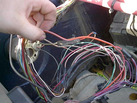 1979 Ford Bronco - A hand manipulates a complex wiring harness, likely for vehicle repair or modification.