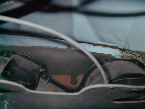 1979 Ford Bronco - The interior of a vehicle shows signs of rust and wear, with visible plastic components and a cable running across the frame.