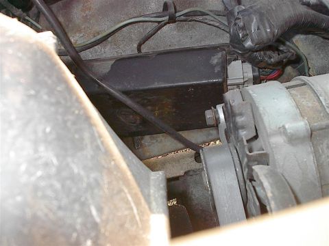 1979 Ford Bronco - Close-up view of engine components including an alternator and a black electrical box.