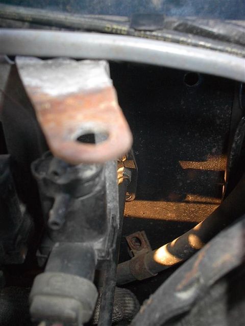 1979 Ford Bronco - Close-up view of engine bay components, including a rusty bracket and various hoses.