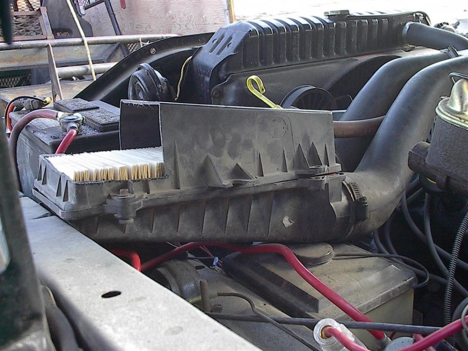 Engine bay showing an air filter box, radiator, and battery. The air filter is a prominent rectangular component with visible filter media