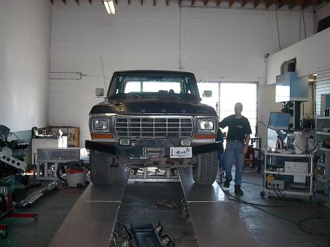 1979 Ford Bronco - Front view of a 1979 Ford Bronco on a lift in a workshop with a man standing next to it.