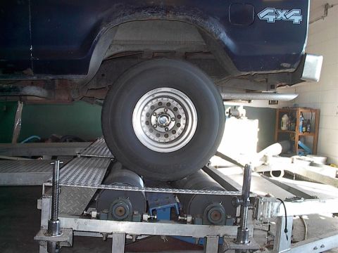 1979 Ford Bronco - The rear wheel of a dark blue SUV is positioned on a dynamometer, with a '4x4' decal visible on the body.