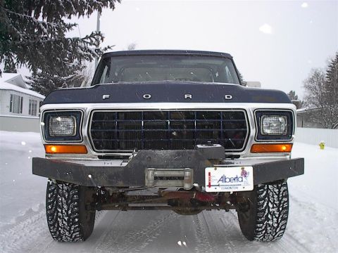 1979 Ford Bronco - A 1979 Ford Bronco is seen from the front, equipped with a winch and an aftermarket bumper, parked in a snowy environment.