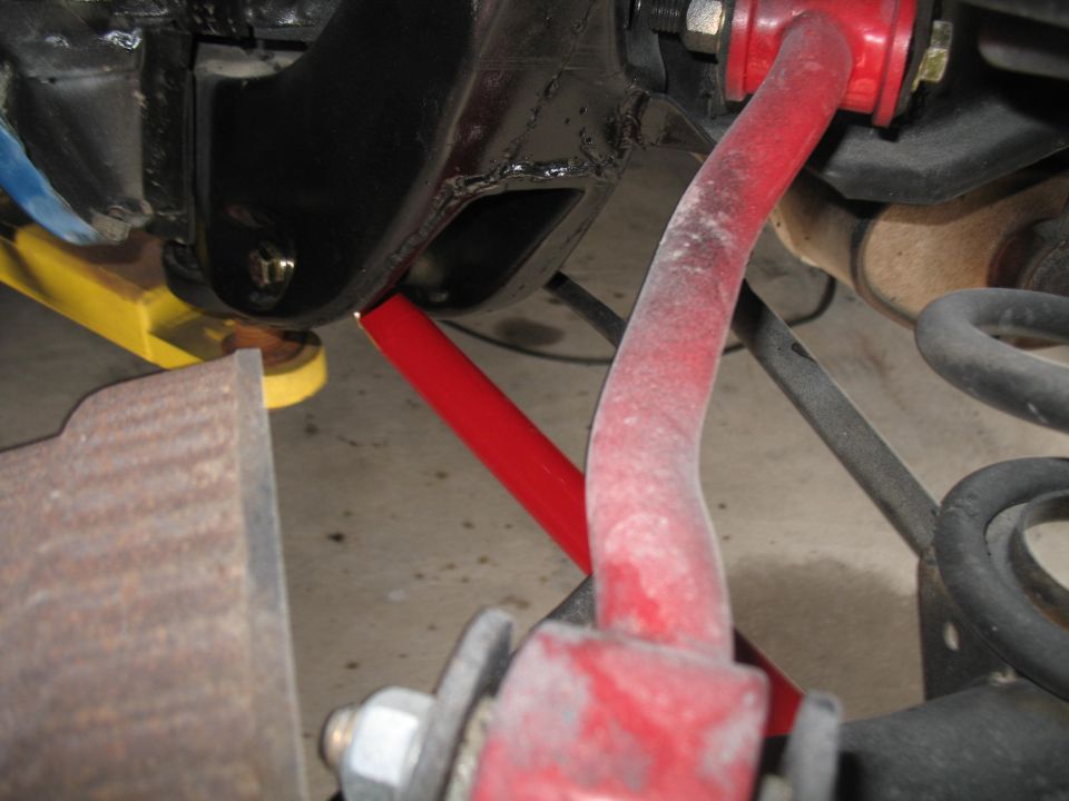 Close-up of red suspension parts and a coil spring under a vehicle
