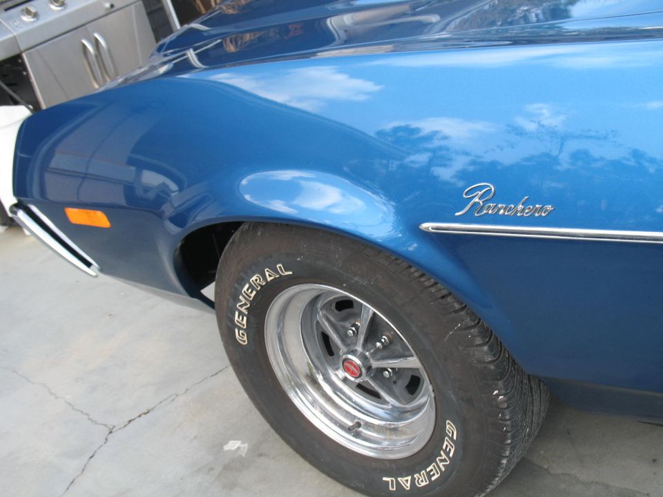Close-up of a blue car's front fender and wheel. The word "Ranchero" is visible on the fender