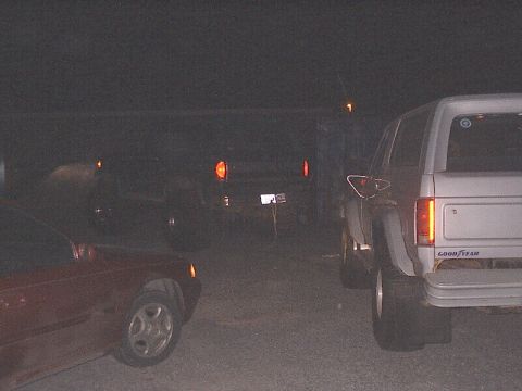 1996 Ford Bronco - A white 1996 Ford Bronco is parked at night, with its brake lights illuminated.