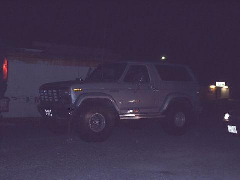 1996 Ford Bronco - A silver Ford Bronco is parked outdoors at night, showing its front three-quarter view.