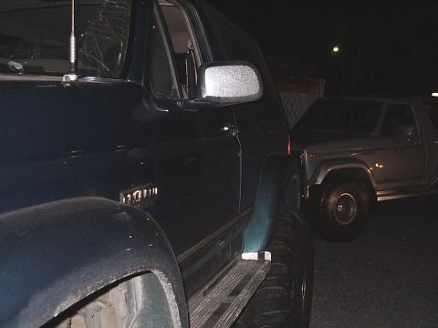 1996 Ford Bronco - A dark green SUV is parked next to a silver SUV at night. The registry claims it is a 1996 Ford Bronco, but the body style suggests an earl…