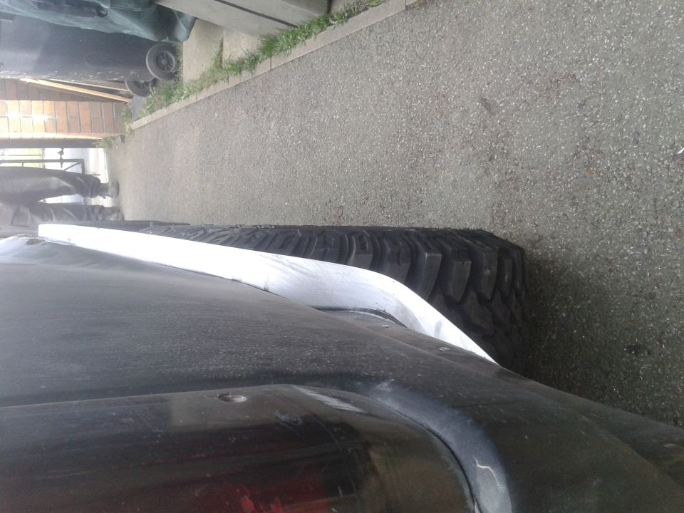 Dark SUV tire and white fender flare, side view, parked on asphalt