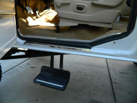 1979 Ford Bronco - The interior of the vehicle shows the driver's side door sill, carpet, and pedals.