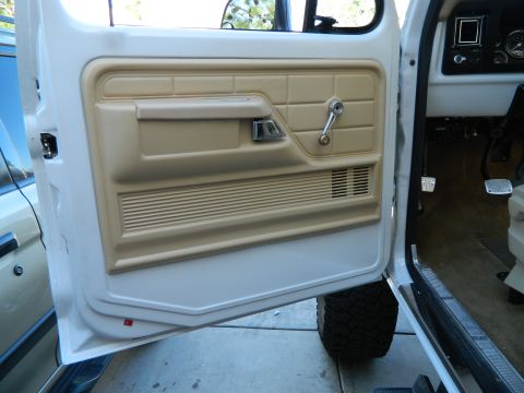 1979 Ford Bronco - Interior view of a 1979 Ford Bronco, showing the door panel, dashboard, and a portion of the tire.