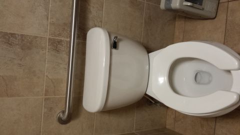 1995 Ford Bronco - A toilet is shown in a tiled bathroom with a metal grab bar on the left.
