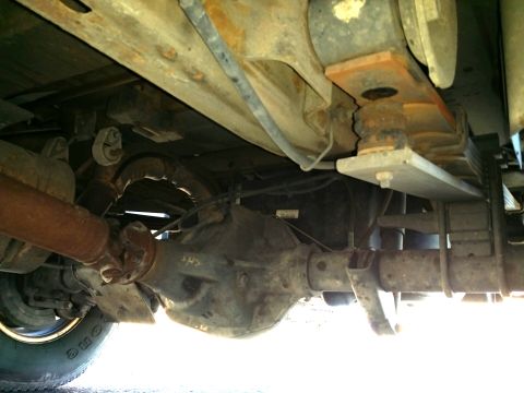 2001 Ford Excursion - The underside of a vehicle shows the rear axle assembly and suspension components, with visible signs of rust.