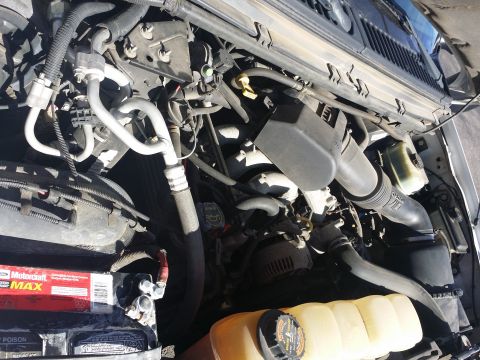2001 Ford Excursion - The engine bay of a vehicle, a Ford Motorcraft Max battery and a Supermotors.net watermark.