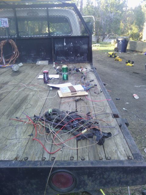 1978 Ford Bronco - Wiring harness and electrical components are scattered on a flatbed trailer, with toy trucks visible in the background.