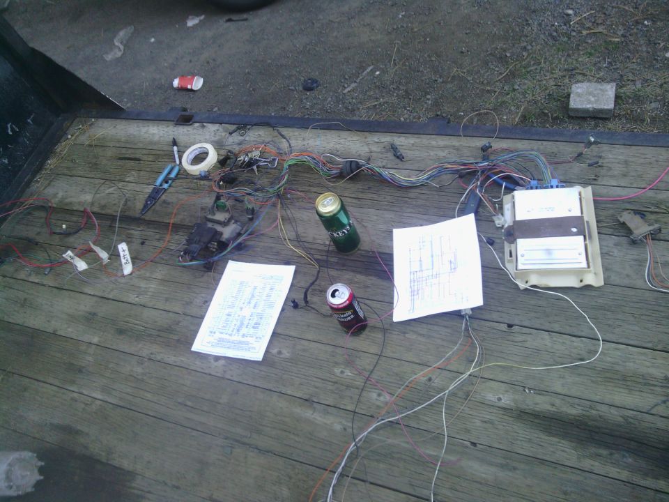 Wiring harness laid out on a wooden surface with two diagrams and two beer cans