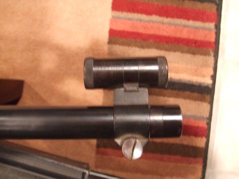 1996 Ford Bronco - A rifle scope is shown mounted on a rifle barrel, with a striped fabric in the background.
