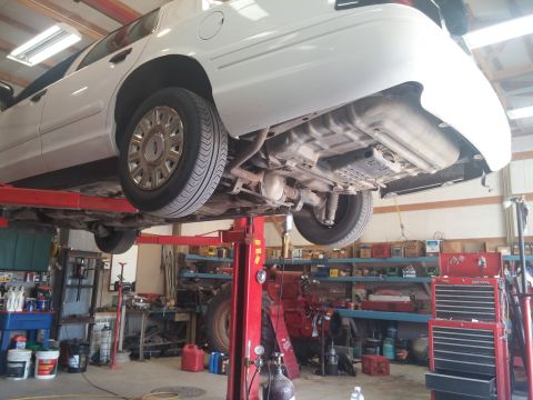 2000 Mercury Grand Marquis - Underside view of a white 2000 Mercury Grand Marquis being serviced on a car lift.