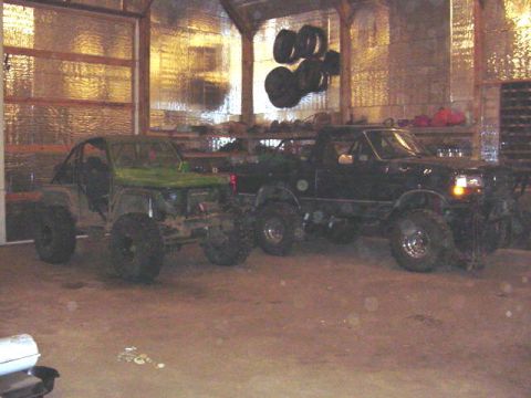 1992 Ford Bronco - Two modified vehicles, including a 1992 Ford Bronco, are stored inside a garage.