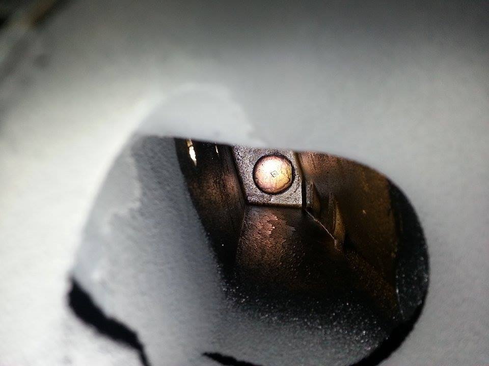 Close-up of a metallic engine part with a circular fastener, showing wear and discoloration