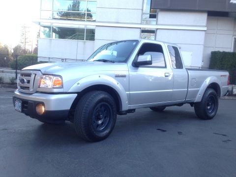 2010 Ford Ranger - A silver Ford Ranger pickup truck is parked in front of a building with large windows.